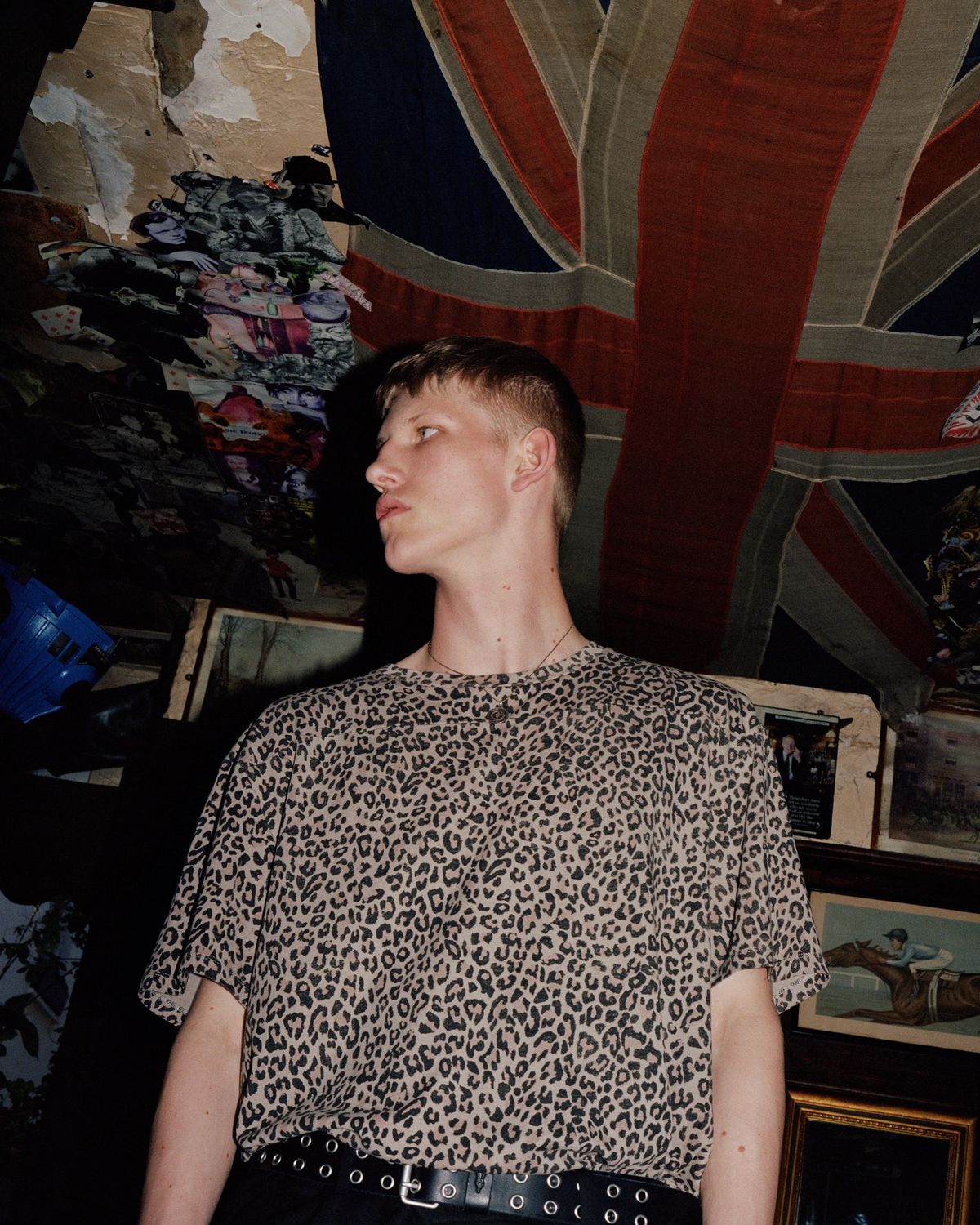 Campaign image of a man standing in front of a background full of UK memorabilia and wearing a leopard print t-shirt.