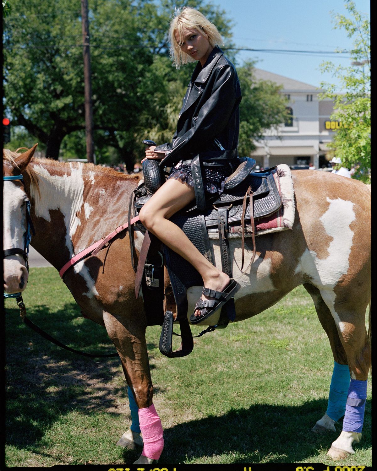Fotografía de una chica sobre un caballo vistiendo una cazadora de cuero negra y unos shorts de nuestra última colección de verano.