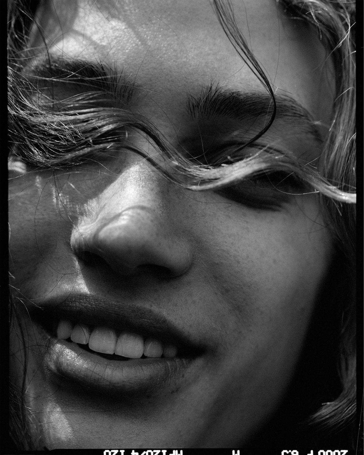 Retrato en primer plano en blanco y negro de una chica con el pelo cubriéndole los ojos.