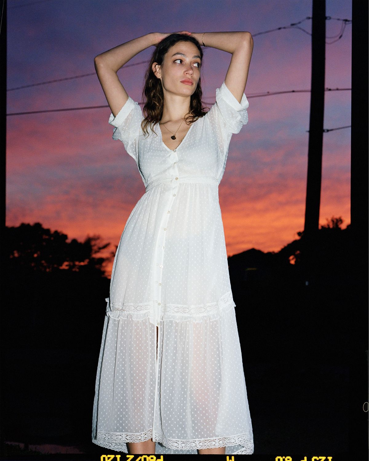 Fotografía de una chica posando al atardecer, vistiendo un vestido largo de topos de nuestra última colección.
