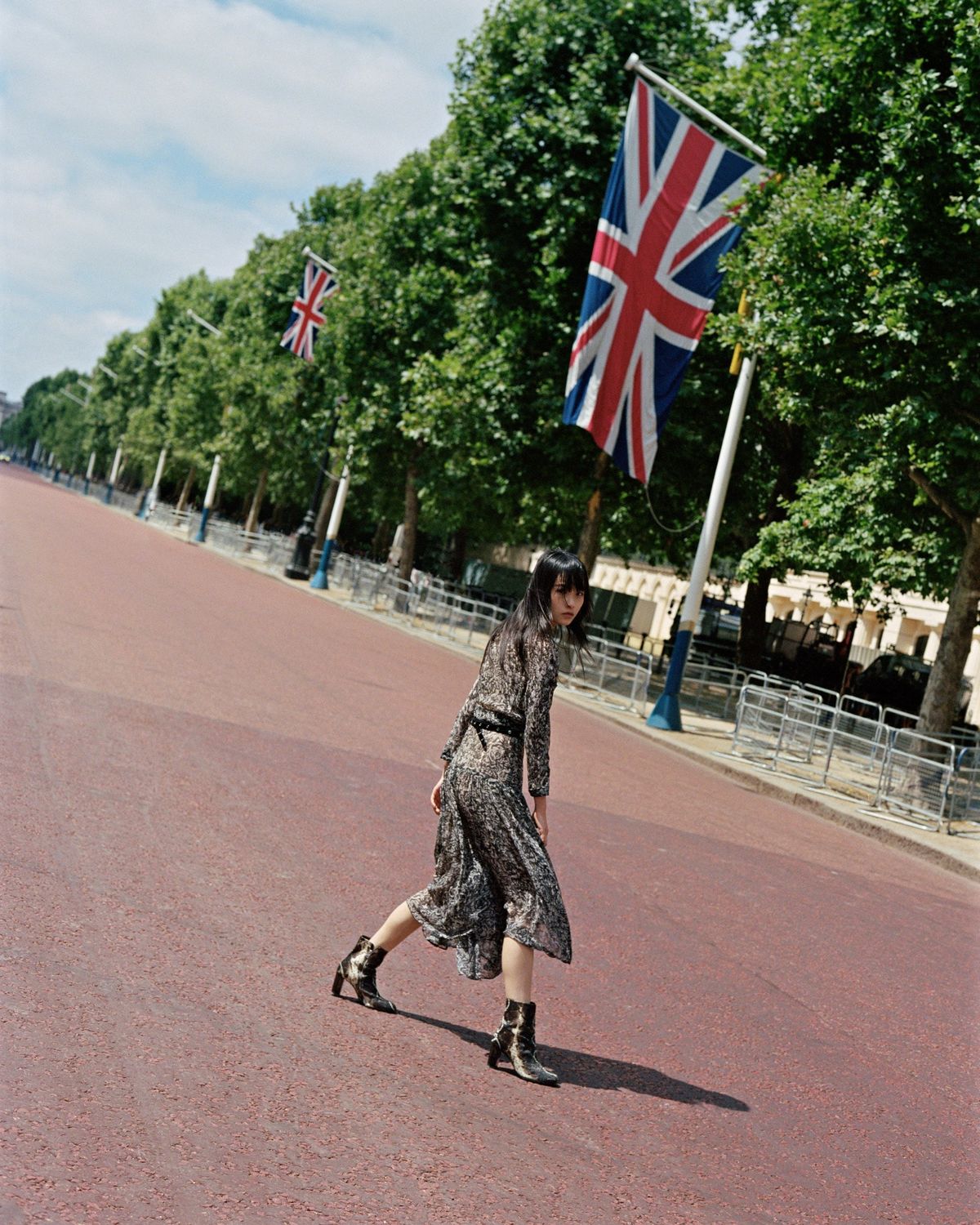Campaign image of a woman in a street of London wearing a long printed dress with printed boots.