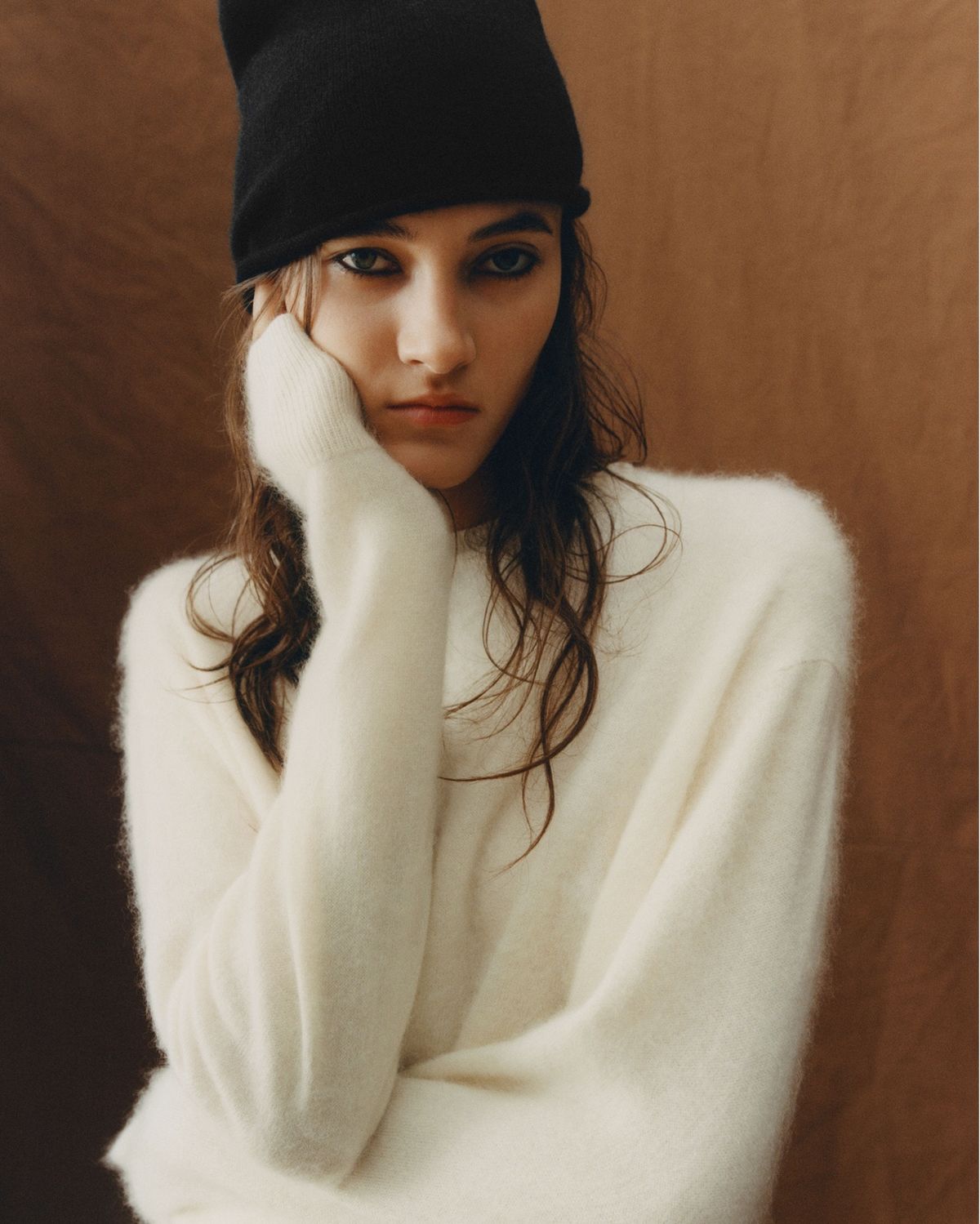 Portrait of a woman wearing a white jumper and black beanie.