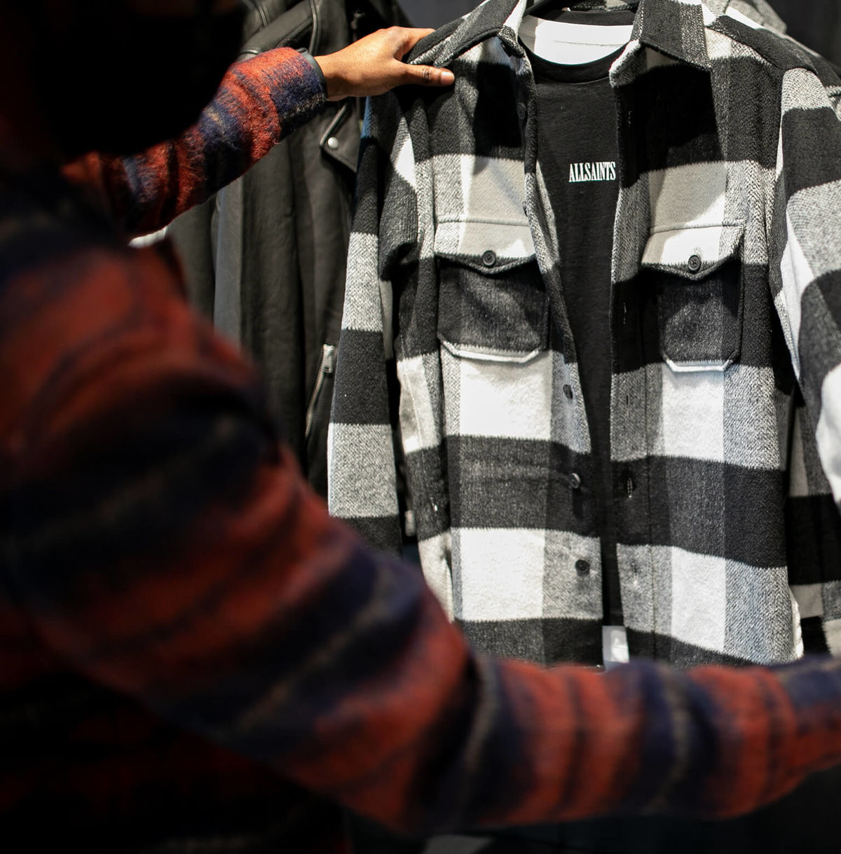 Un membre de notre personnel tient une chemise noire et blanche à carreaux assemblée à un t-shirt noir.