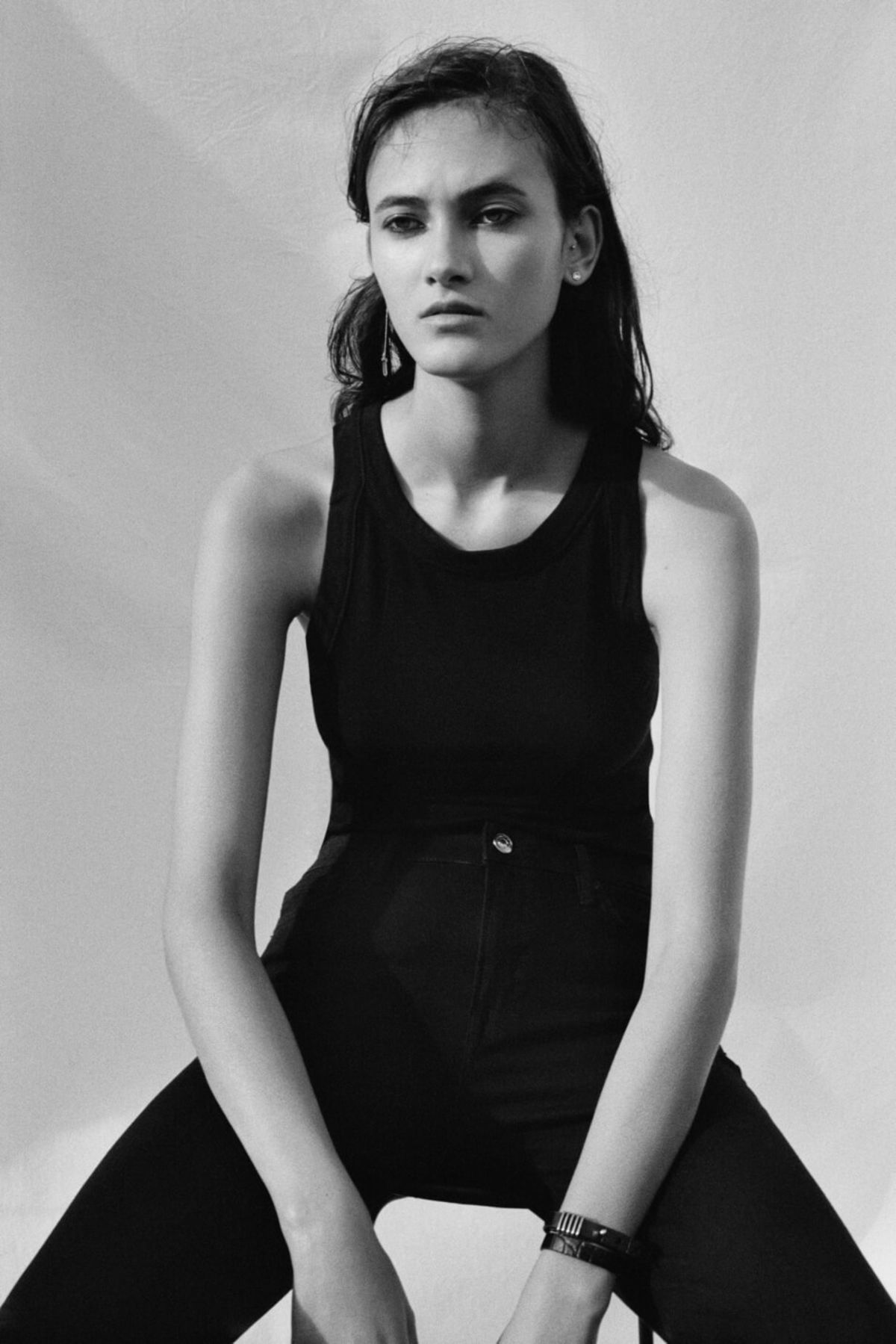 Black and white portrait of a woman wearing black jeans and a black tank top with some of our jewellery pieces.