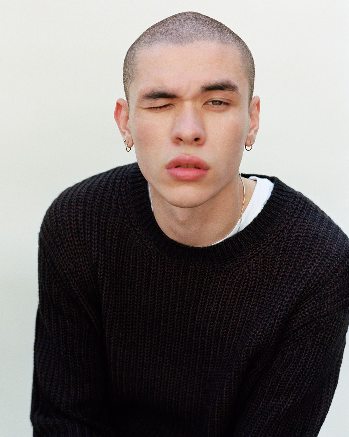 Portrait of a man winking at the camera and wearing a chunky dark jumper from our latest collection.