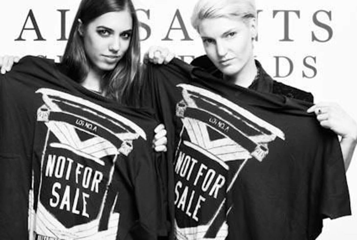 Schwarz-Weiß-Bild von zwei Prominenten, die ein Not For Sale T-Shirt halten.