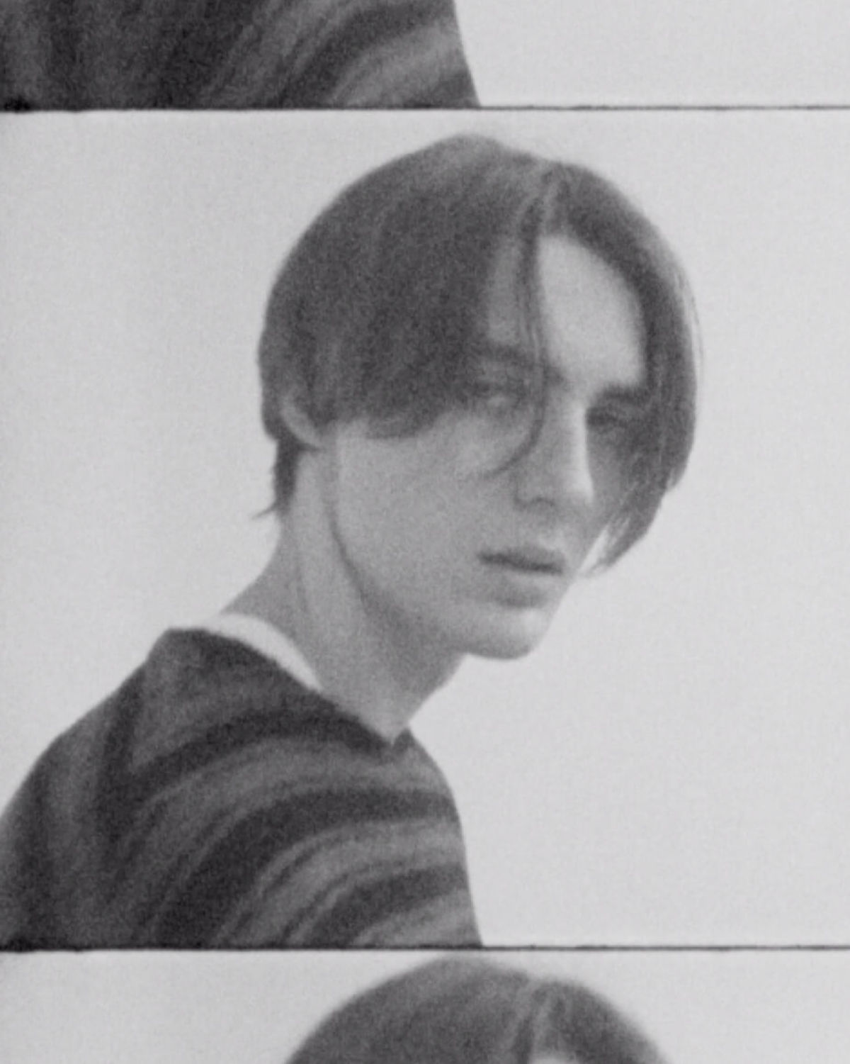 Video placeholder. Black and white close up portrait of a man wearing a striped jumper over a white t-shirt.