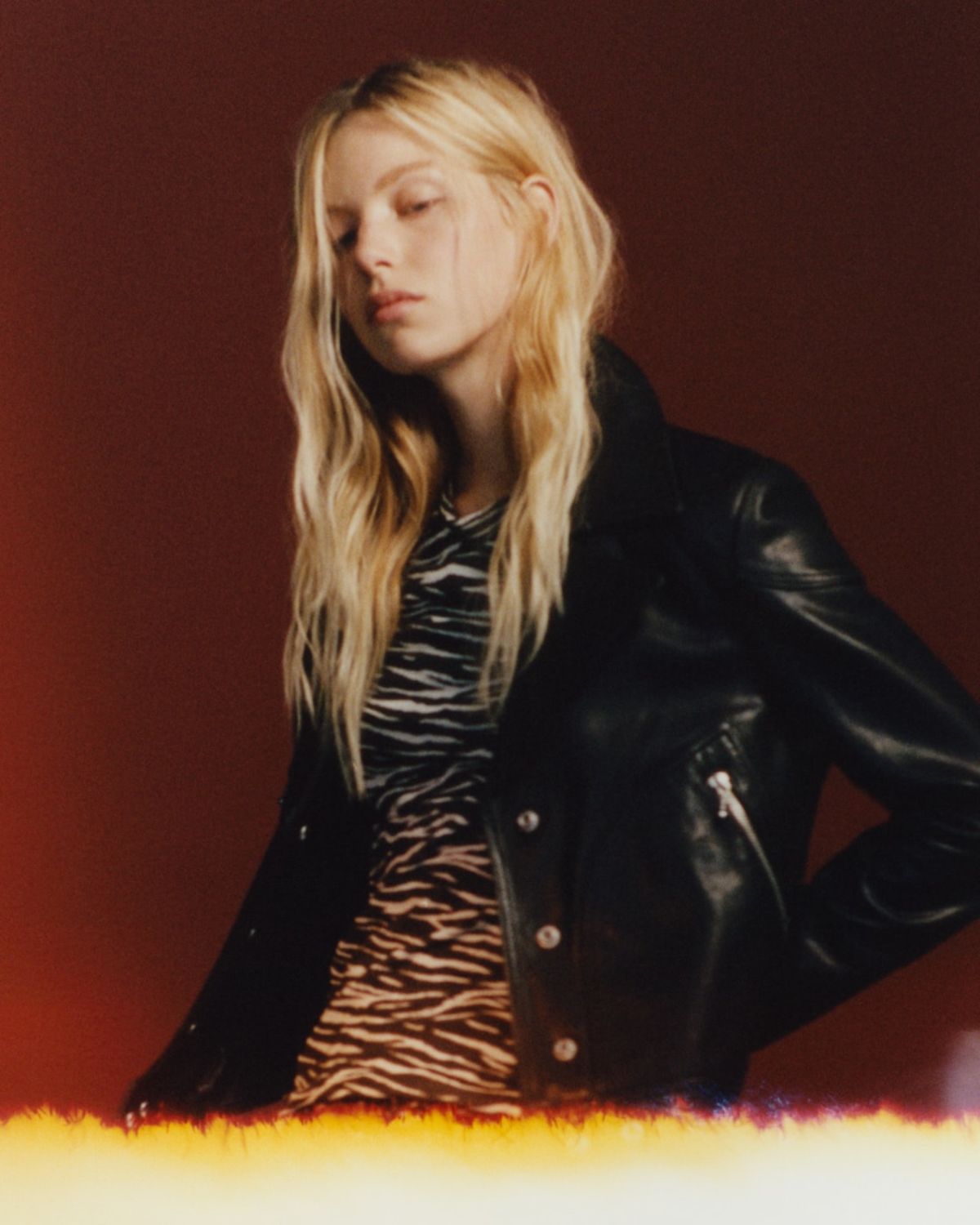 Portrait of a woman wearing a zebra printed t-shirt under a black leather biker jacket.
