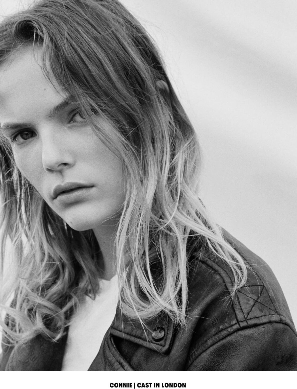CONNIE | CAST IN LONDON. Black and white close up portrait of a blonde woman wearing a black leather jacket over a white t-shirt.