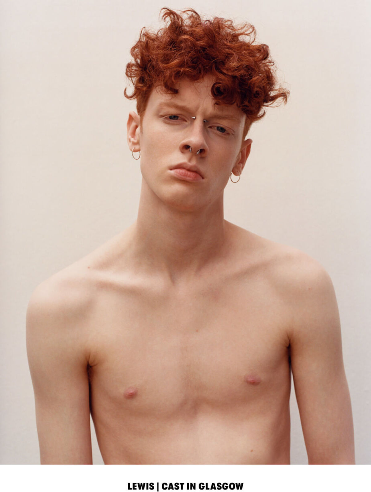 LEWIS | CAST IN GLASGOW. Portrait of a shirtless man with a couple of piercings on his nose and earings.