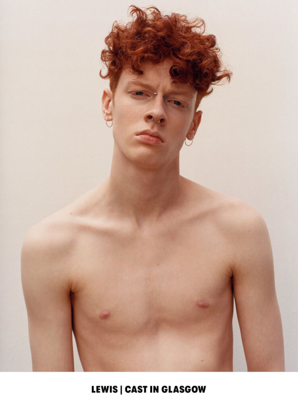 LEWIS | CAST IN GLASGOW. Portrait of a shirtless man with a couple of piercings on his nose and earings.