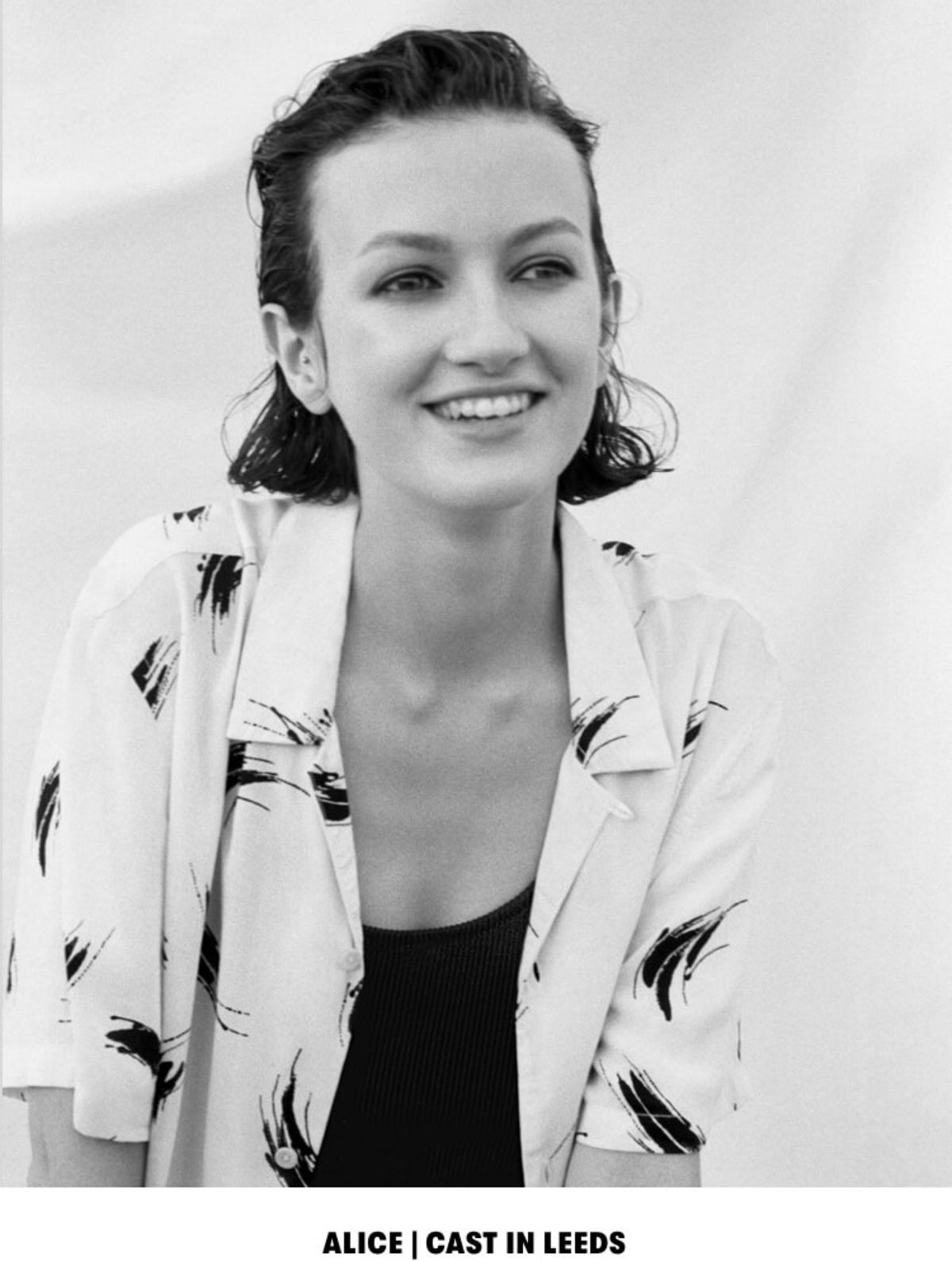 ALICE | CAST IN LEEDS. Black and white portrait of a woman wearing a printed shirt over a black tank top.