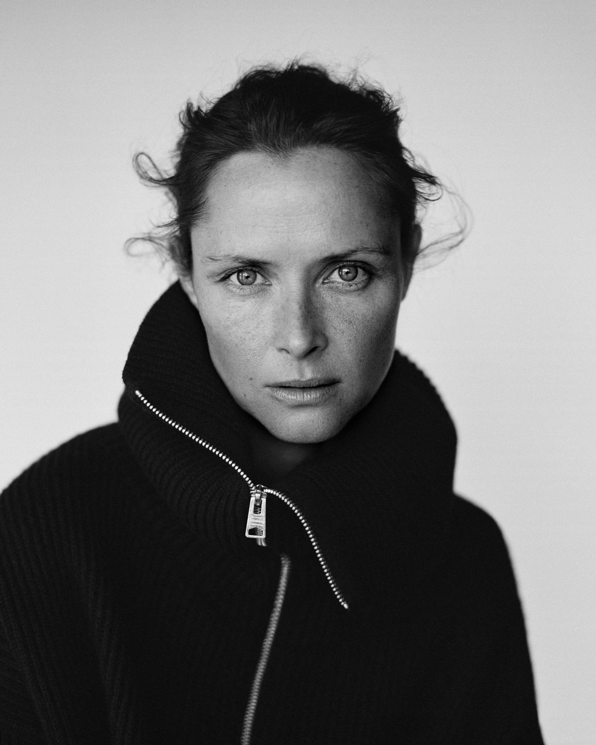 Black and white portrait of a woman wearing a black zipped roll neck jumper.