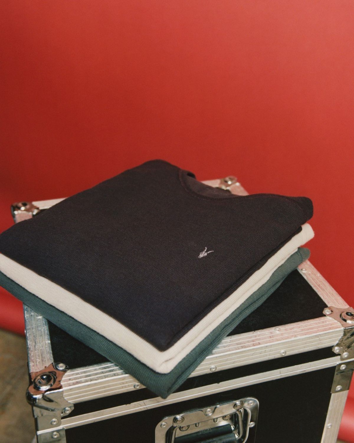 Image of a stak of three Ramskull t-shirts in front of a red background.