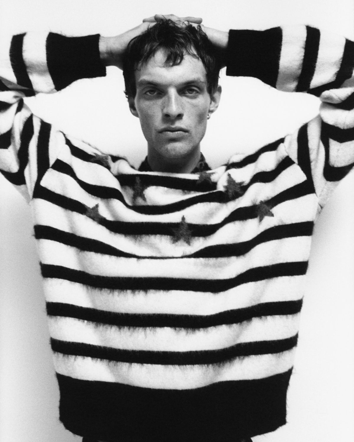 Black and white image of a man wearing a stripes and stars printed jumper .