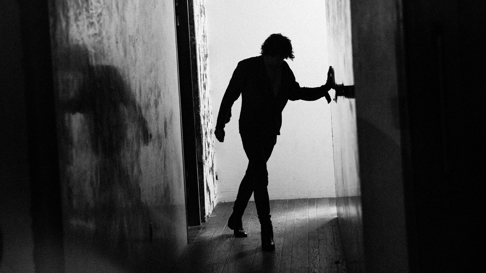 Black and white image of Barns Courtney walking in a corridor backstage.