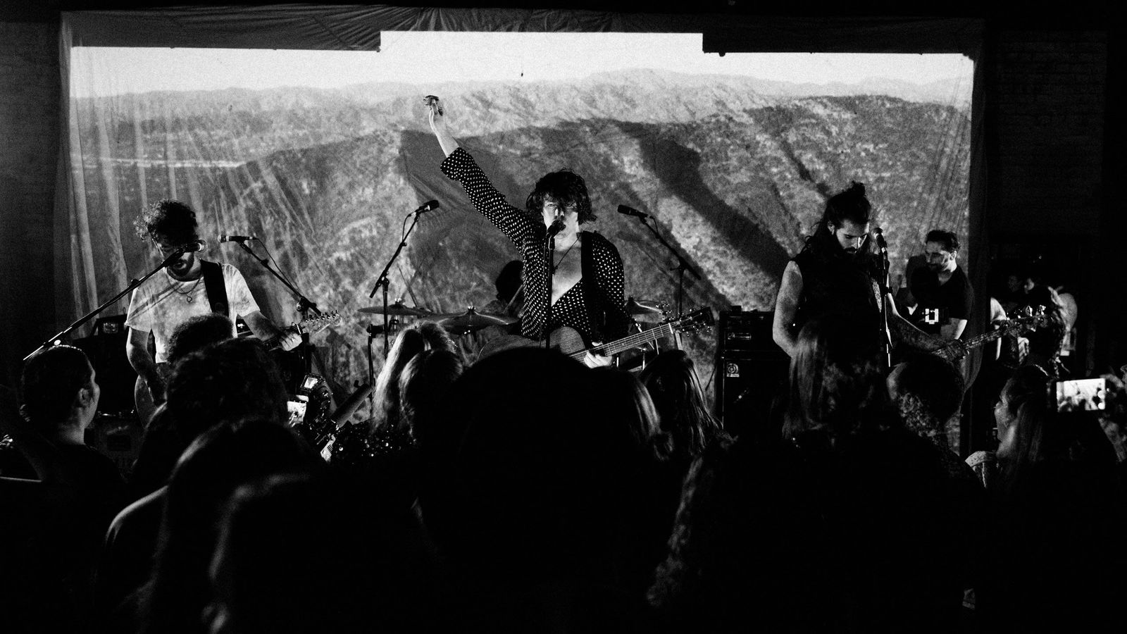 Immagine in bianco e nero di Barns Courtney che canta con la sua band.