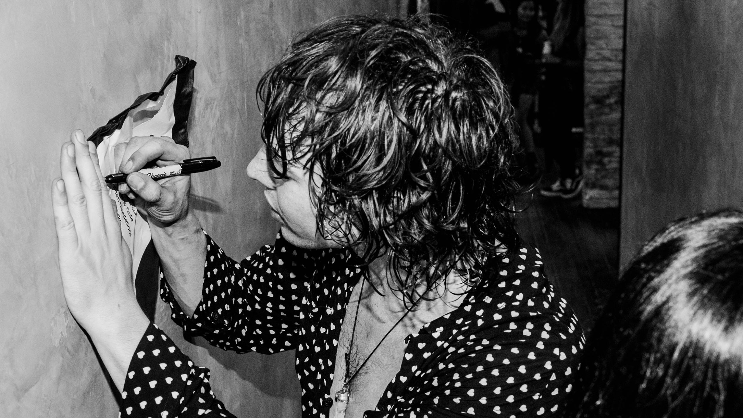 Immagine in bianco e nero di Barns Courtney che firma autografi.