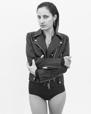 Black and white image of a woman wearing a black leather jacket above a black swimsuit.