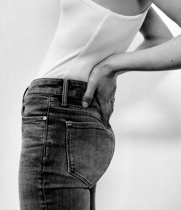 Back shot of a woman wearing black jeans and a white t-shirt.