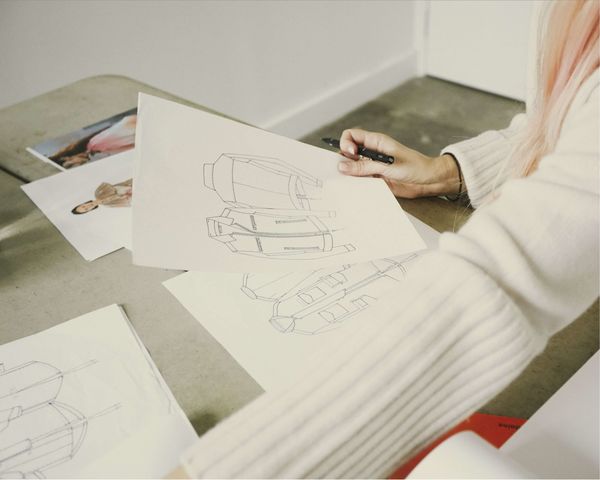Eine Frau bearbeitet eine Skizze einer Lederjacke für Herren.