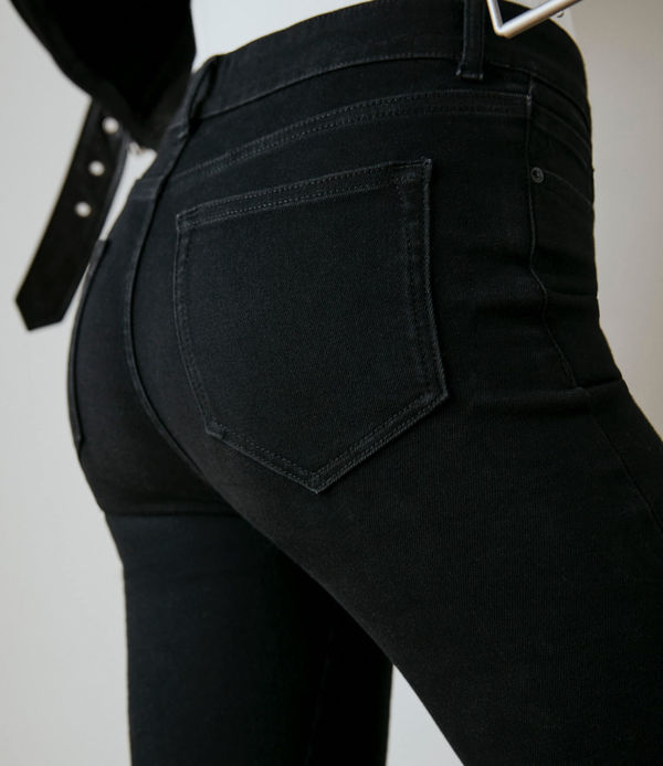 Back shot of a woman wearing black jeans and a leather jacket.