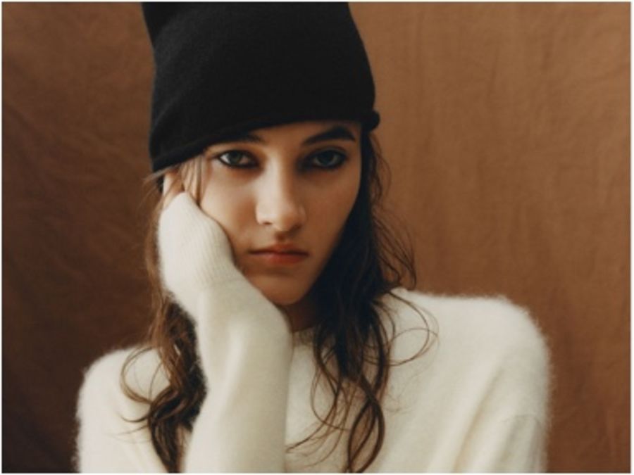 Portrait of a woman wearing a white jumper with a black beanie.