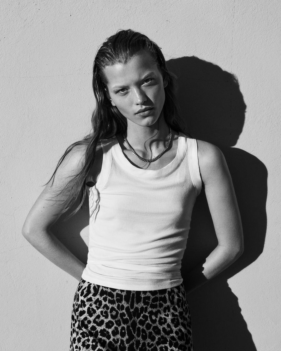 Ritratto in bianco e nero di una donna che indossa una canotta bianca con una gonna leopardata.