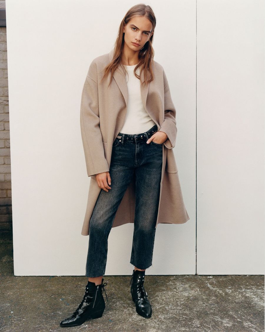 Image of a woman wearing dark blue denim jeans with a white t-shirt, camel coloured coat and black leather boots.