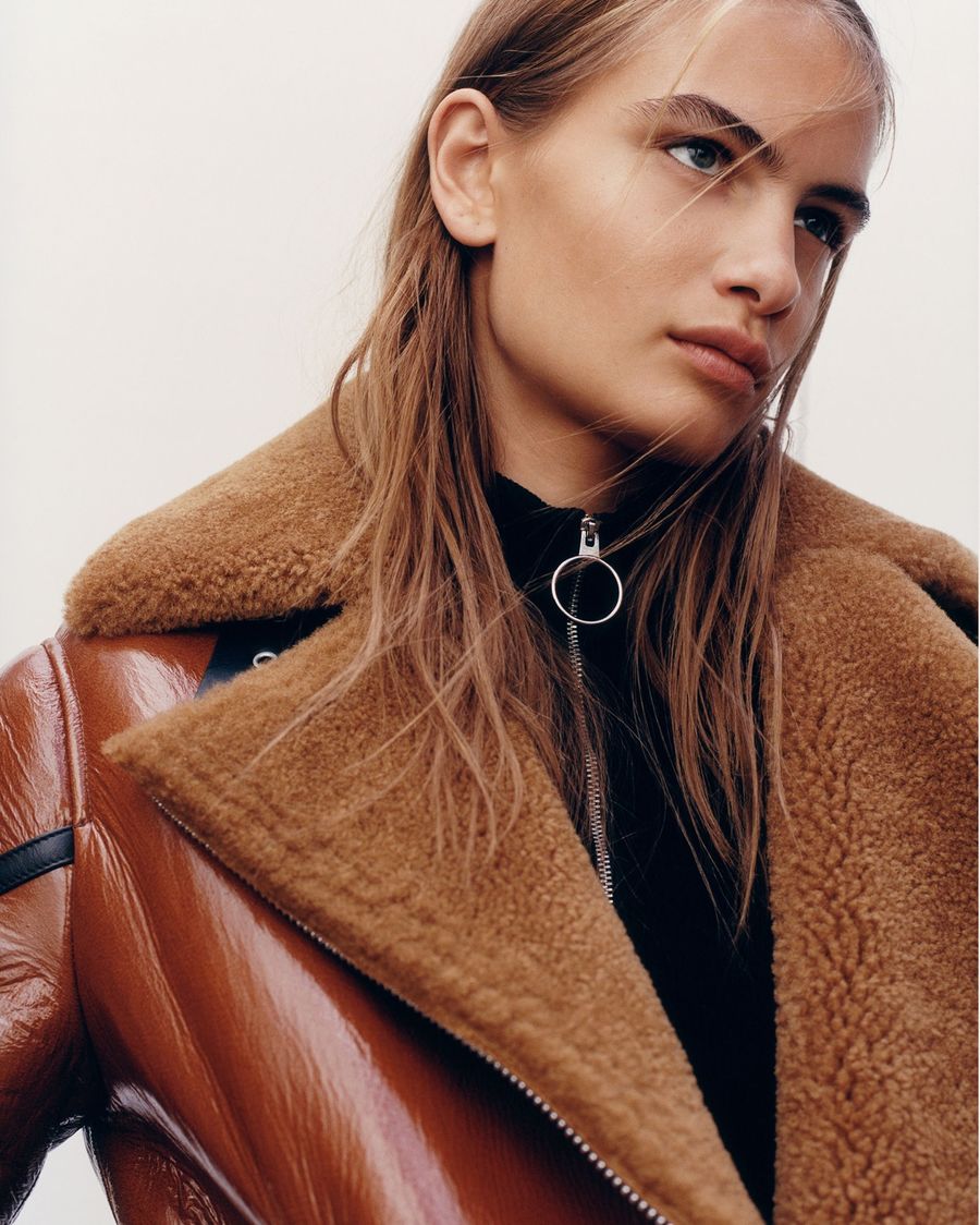 Close up of a woman wearing a brown shearling jacket.