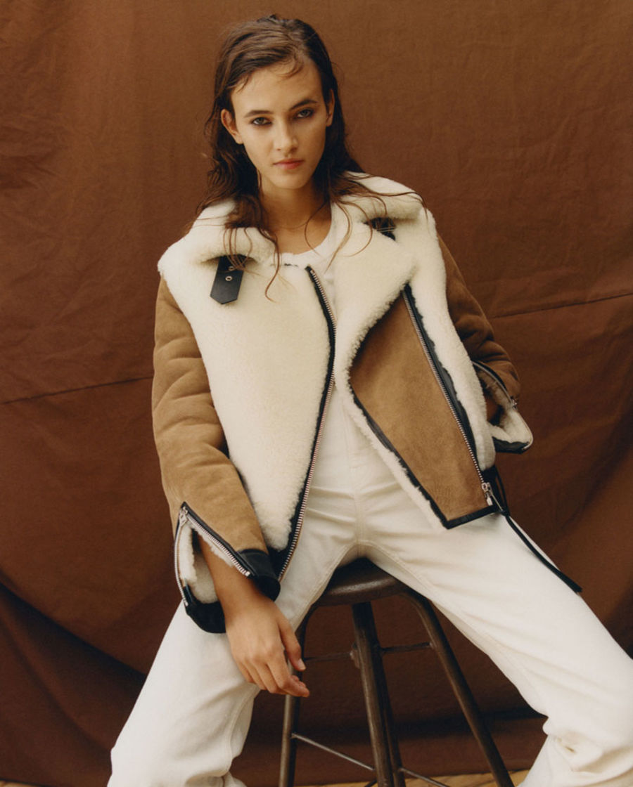 Immagine di una donna che indossa una giacca shearling bianca e beige con una t-shirt bianca e un paio di jeans bianchi.
