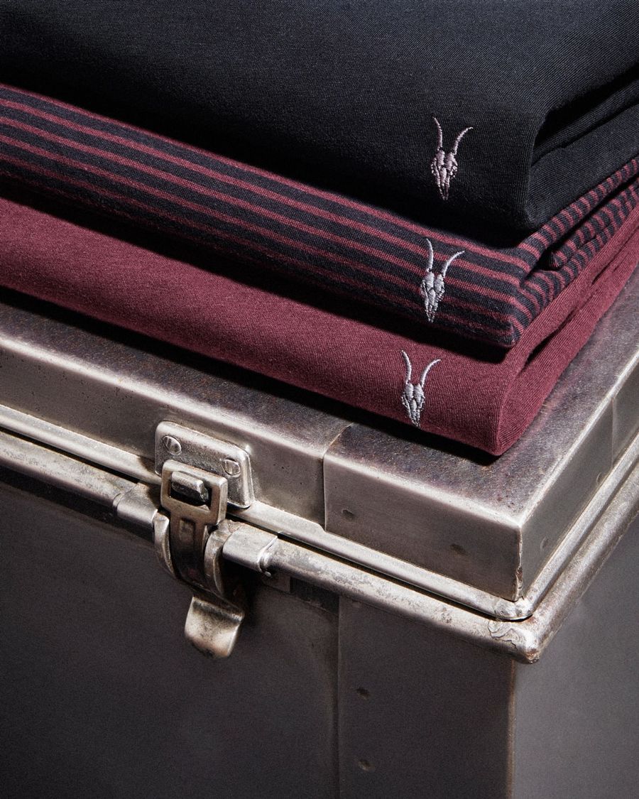 Close up of a pile of neatly folded red and black Ramskull t-shirts.