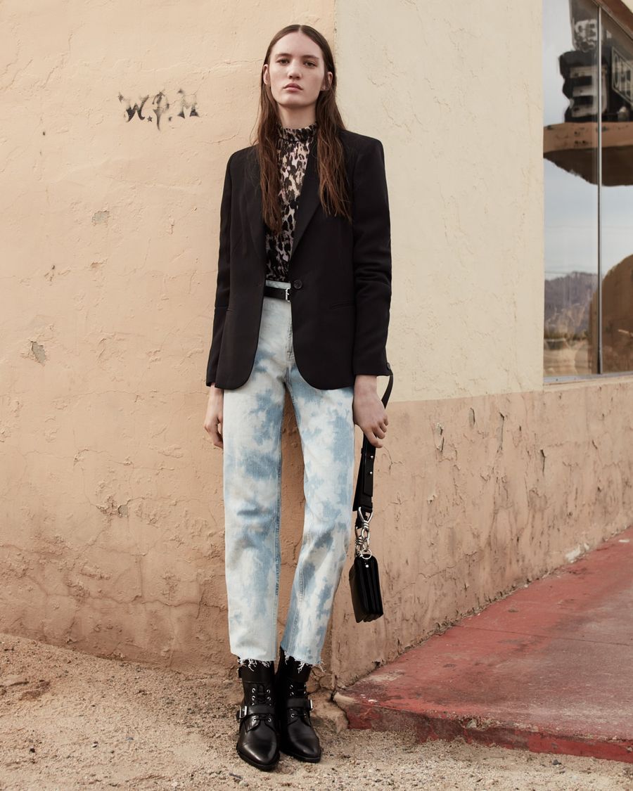 Image of a woman wearing a leopard printed top with a black blazer, acid washed denim jeans and black leather boots.