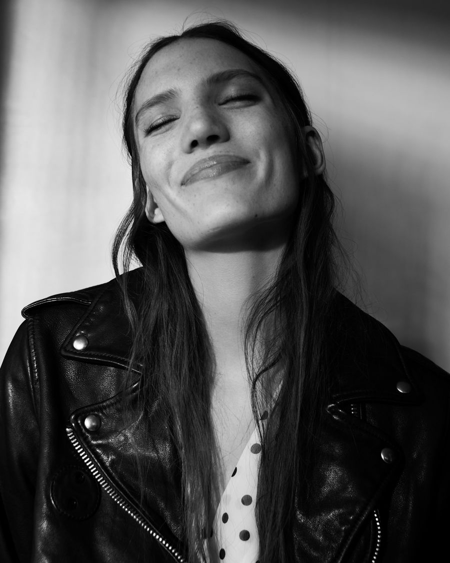 Black and white portrait of a woman wearing a black leather biker jacket over a printed dress.