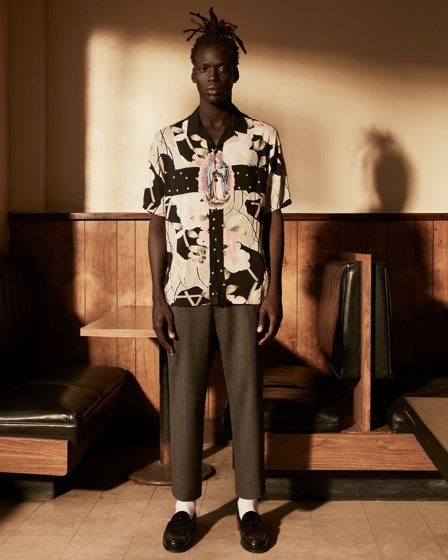 Image of a man wearing a printed Hawaiian shirt with grey tailored trousers and black loafers.