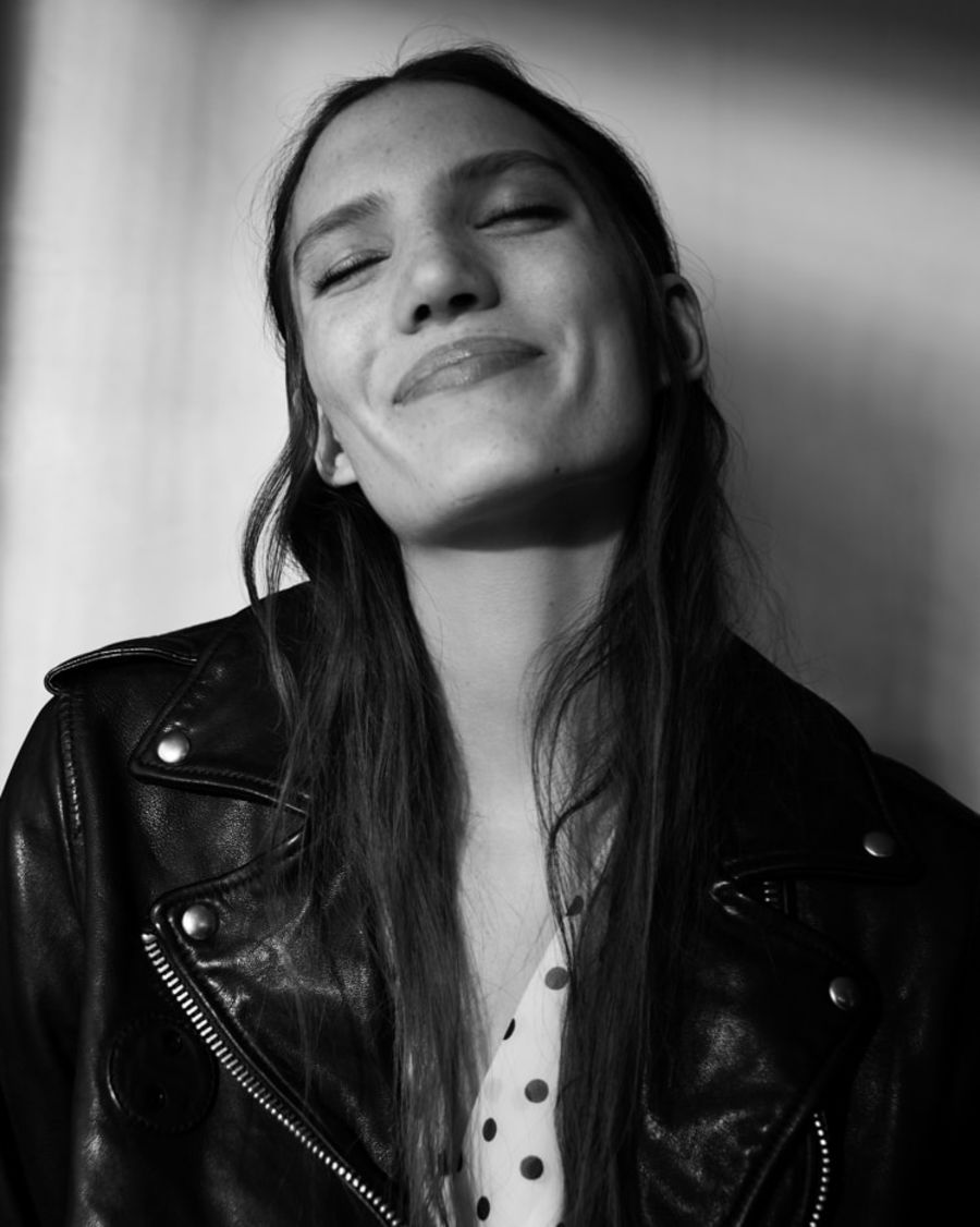 Imagen en blanco y negro de una mujer con una chamarra de cuero negro sobre una blusa estampada.