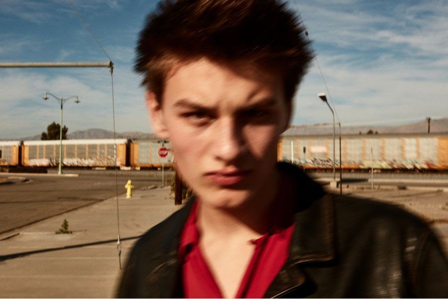 Verschwommenes Portraitfoto von einem Mann, der eine schwarze Lederjacke und ein rotes Hemd trägt.