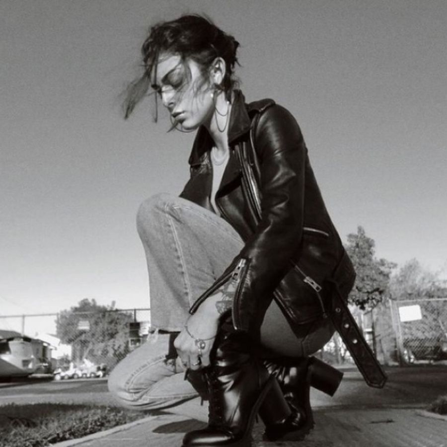 Schwarz-weißes Foto von einer Frau, die eine Lederjacke, Jeans und Stiefel trägt.