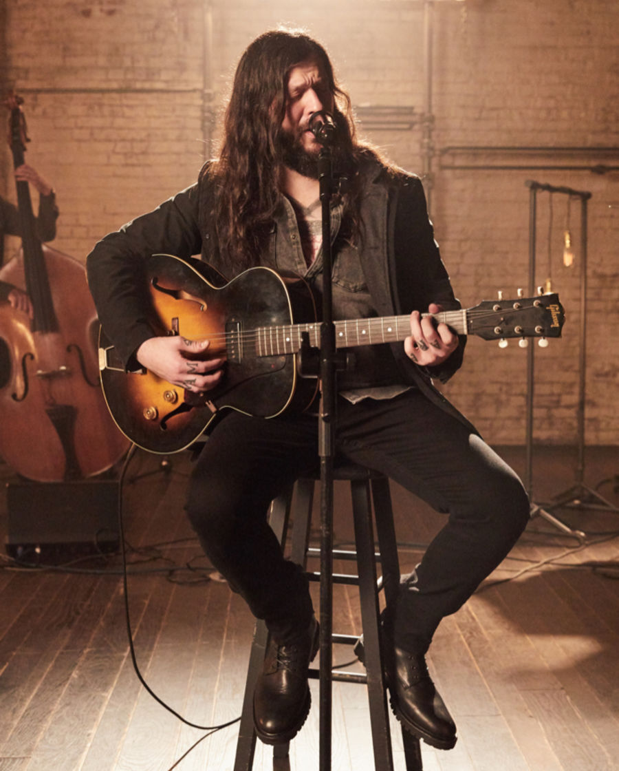 Shawn James playing guitar during the recording of our latest LA Sessions wearing a grey denim shirt with a black leather blazer and black jeans.