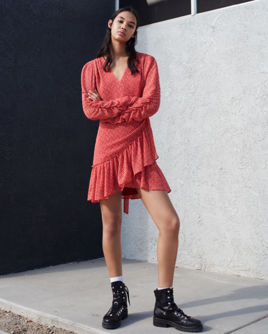 Woman wearing a red and white heart-printed dress with black leather boots.