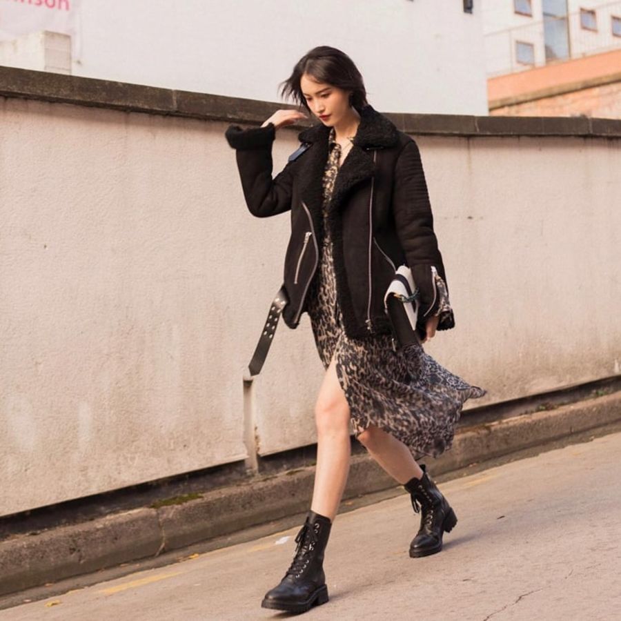 User Generated picture of a woman walking in the street wearing a printed dress and black shearling jacket from our latest collection.