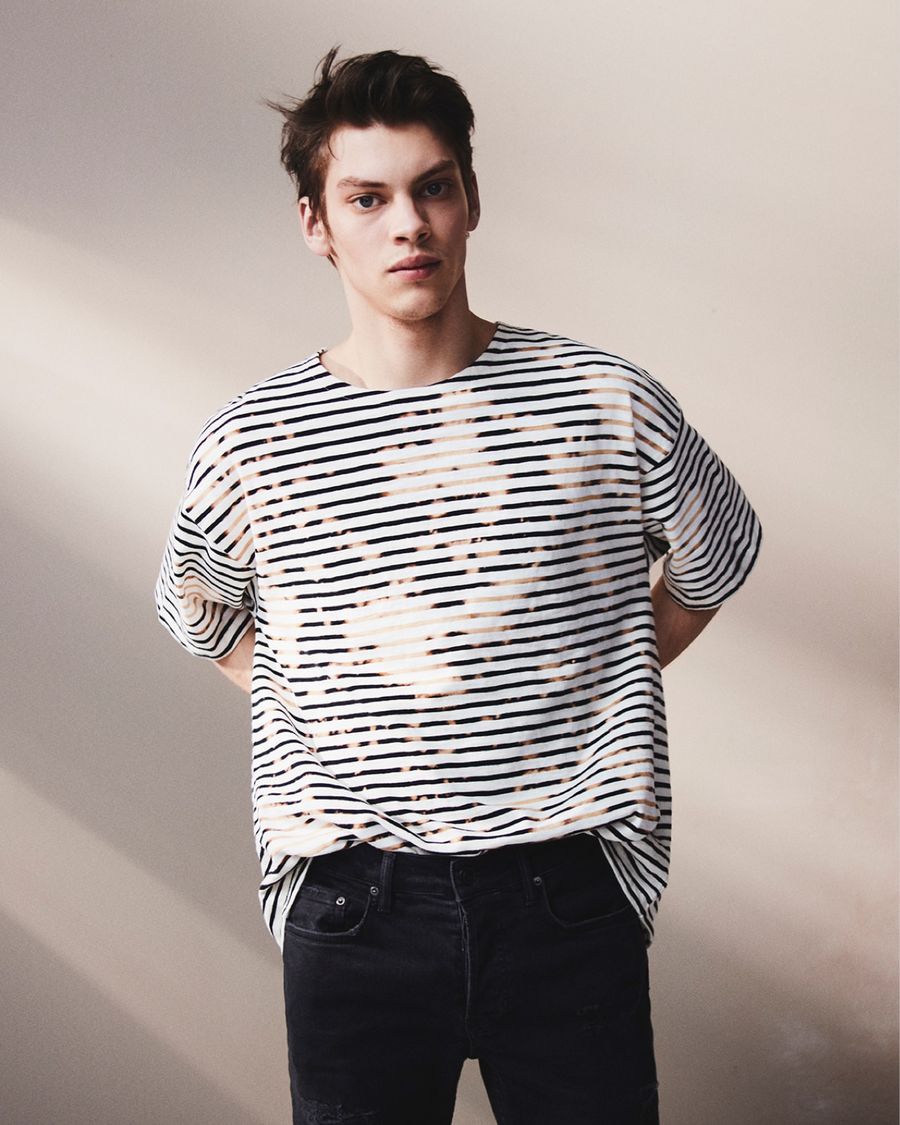 Immagine di un uomo che indossa una t-shirt a righe con jeans neri skinny.