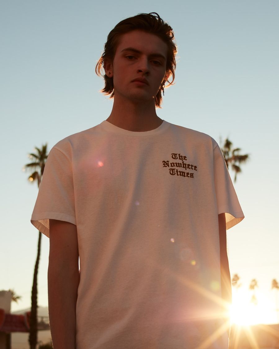 Portrait of a man wearing a white t-shirt with red embroidery on the chest.