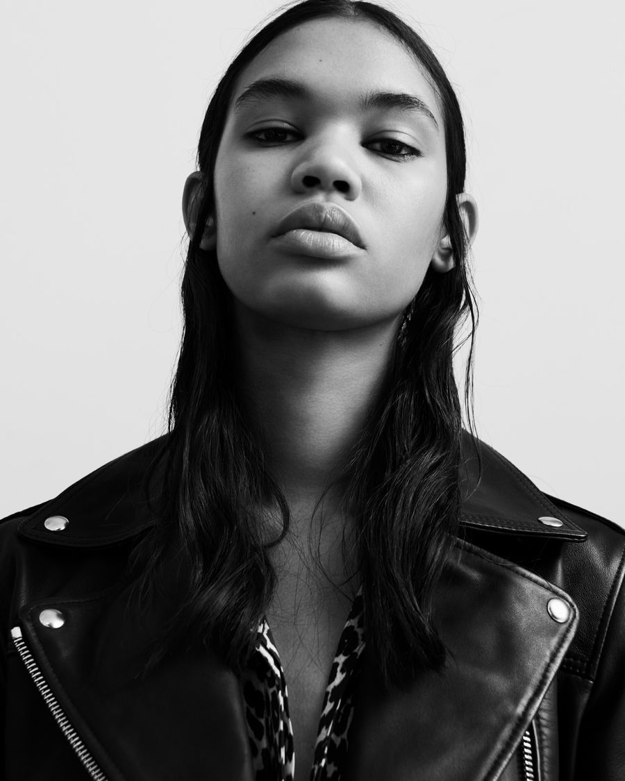 Black and white portrait of a woman wearing a black leather biker jacket over a printed shirt.