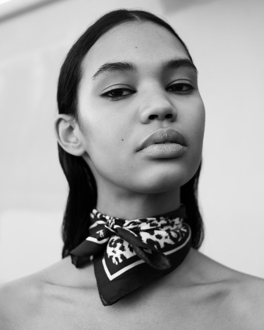 Black and white portrait of a woman wearing a thin scarf around her neck.