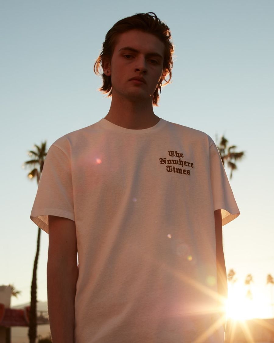 Portrait of a man wearing a white t-shirt with red embroidery on the chest.