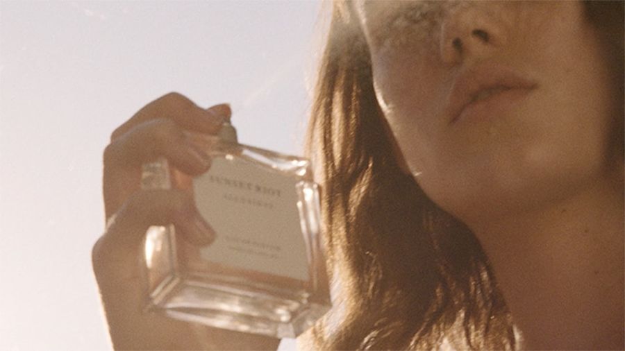 Image of a woman holding our Sunset Riot perfume.