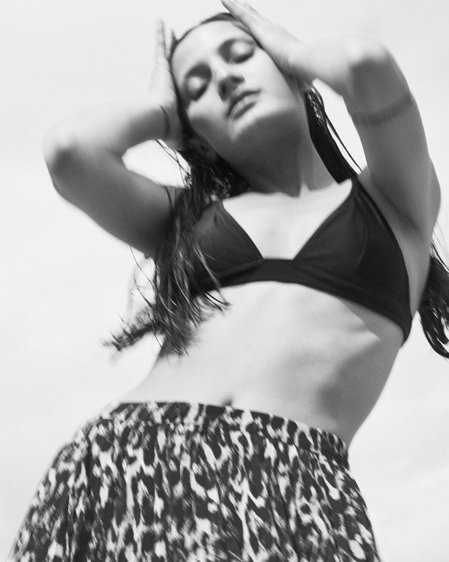 Black and white portrait of a woman wearing a black bikini top with a leopard printed skirt.