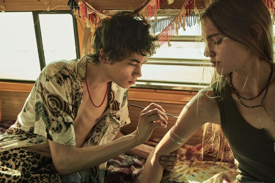 Campaign image of a man painting on a woman's arm at the back of a van, both wearing items from our latest collection.
