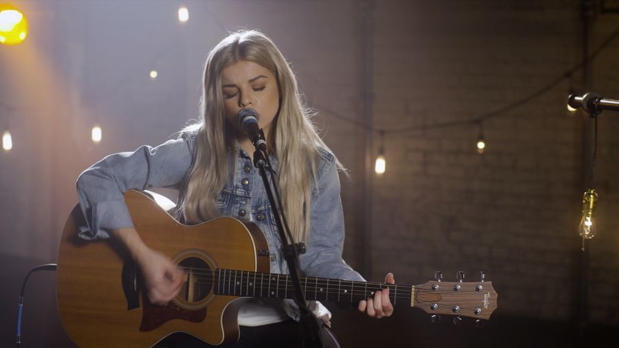 Ivy Adara playing guitar during the recording of our latest LA Sessions wearing a light blue denim jacket with a white t-shirt and black jeans.